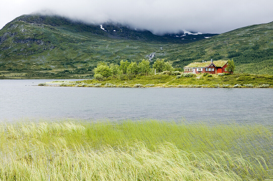 Red cottage on tiny island in a small lake, Norway