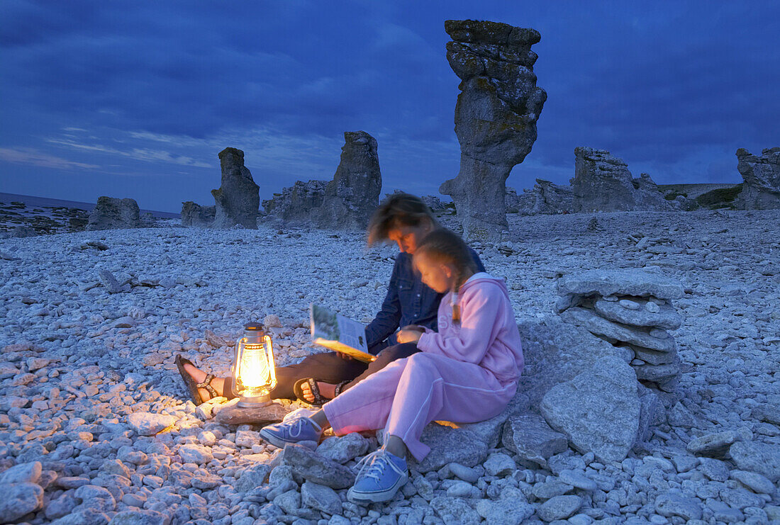 Mother and daughter on beach with sea stacks