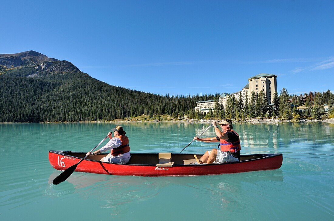 Couple in canoe in front of the hotel Castle Lake Louise, Banff National Park, Rocky Mountains, Alberta, Canada
