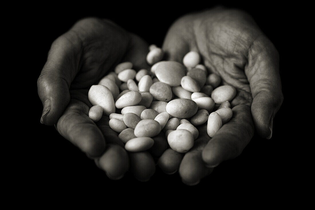 Hands that offer white stones, polished  Means the whisper of water  Conceptual  Black and white
