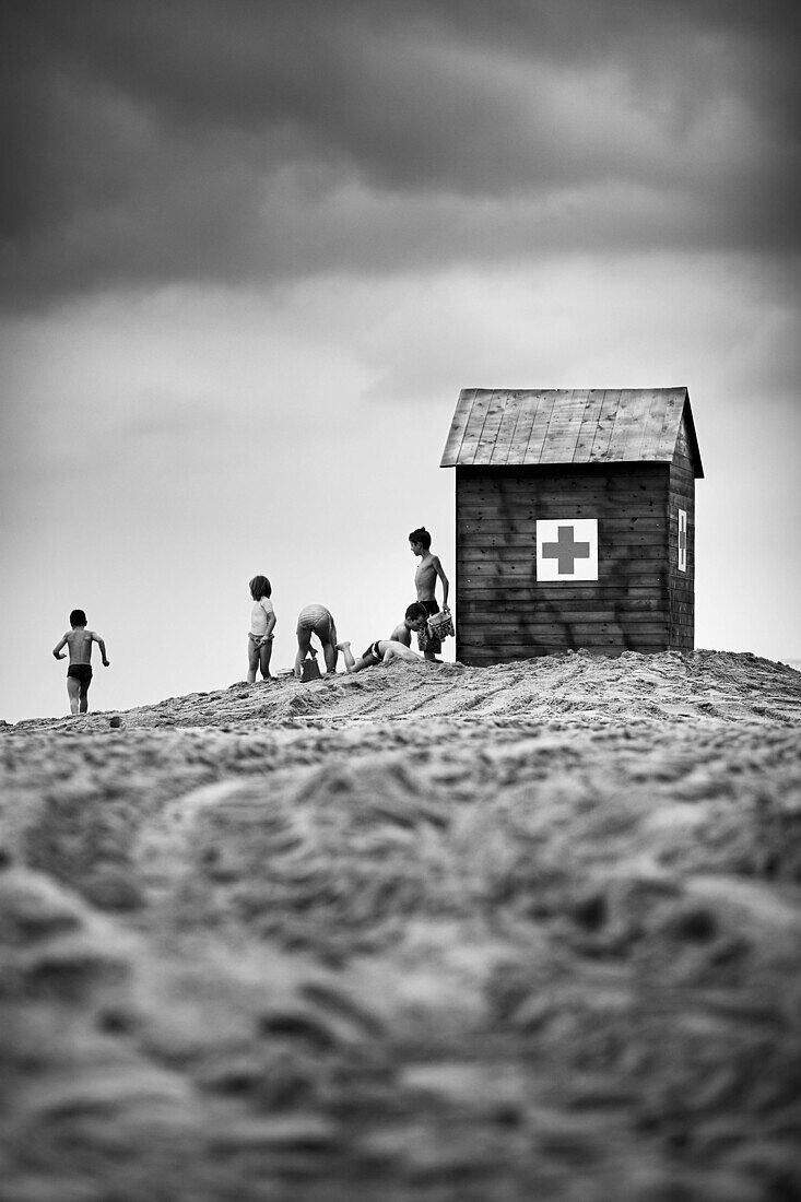 Children playing on the beach next to the hut of the Red Cross