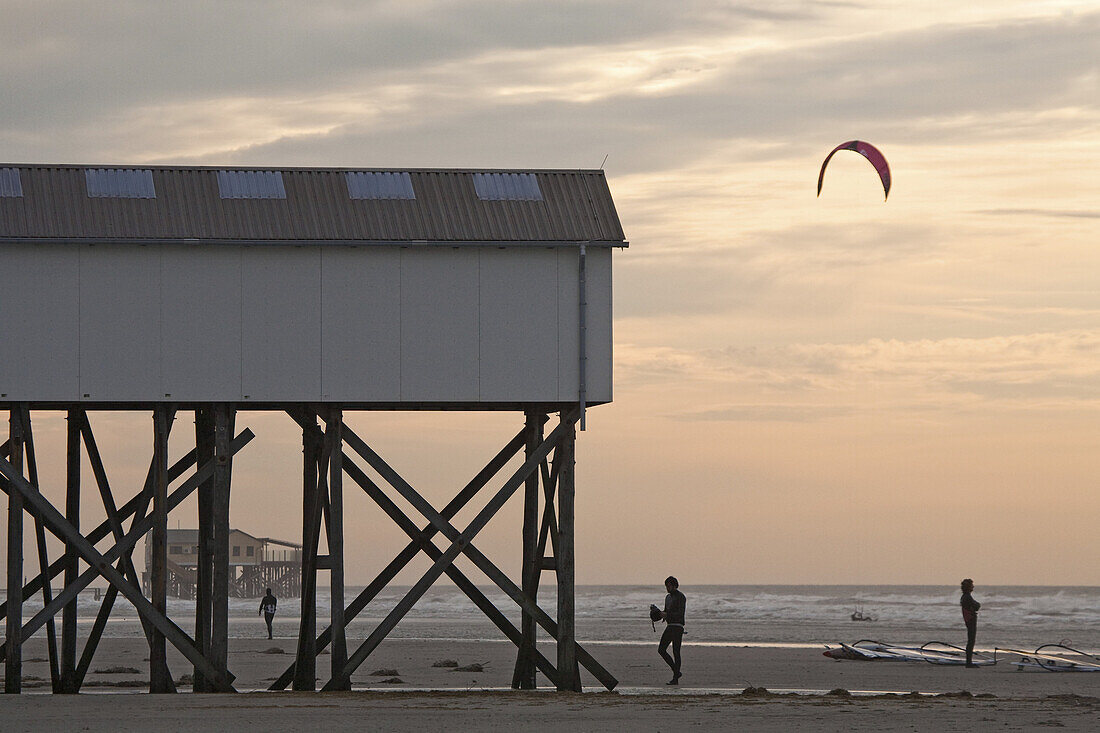 Buildings on stilts, kite surfer on the beach at St Peter-Ording, Schleswig-Holstein, North Sea coast, Germany