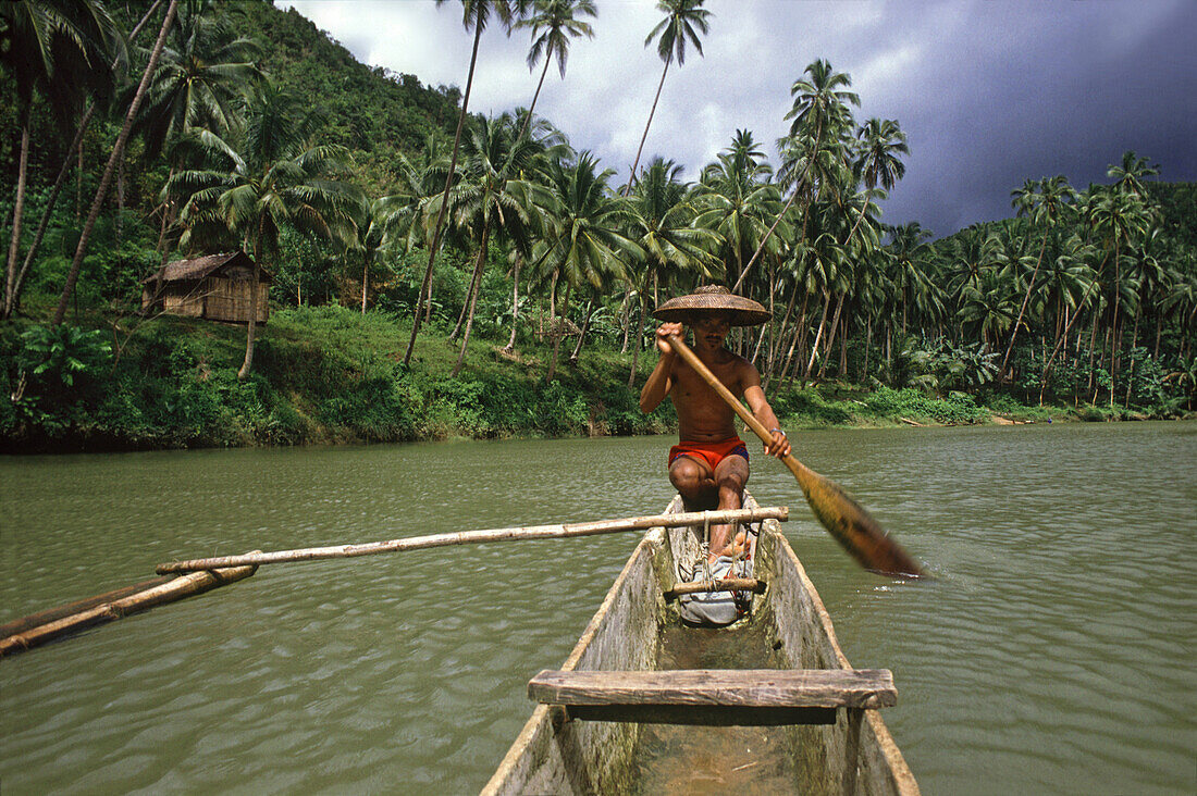 Fisherman paddling an outrigger boat on Loboc River, Bohol Island, Philippines, Asia