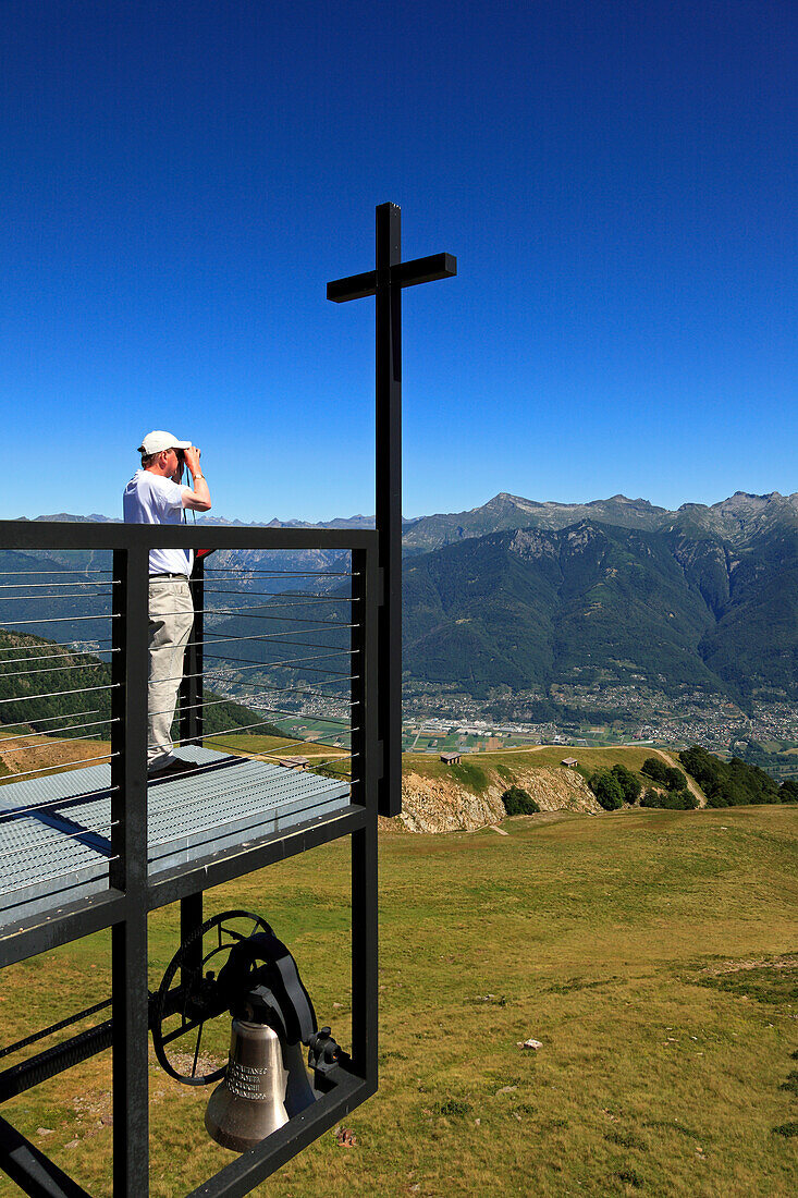 Man with binoculars admiring the view from the chapel Santa Maria degli Angeli, (Architect: Mario Botta), Alpe Foppa, mountain hike to Monte Tamaro, Ticino, Switzerland