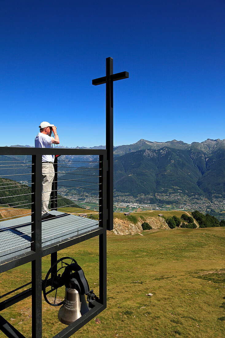 Mann blickt mit Fernglas von der Kapelle Santa Maria degli Angeli (Architekt: Mario Botta), Alpe Foppa, Bergwanderung zum Monte Tamaro, Tessin, Schweiz