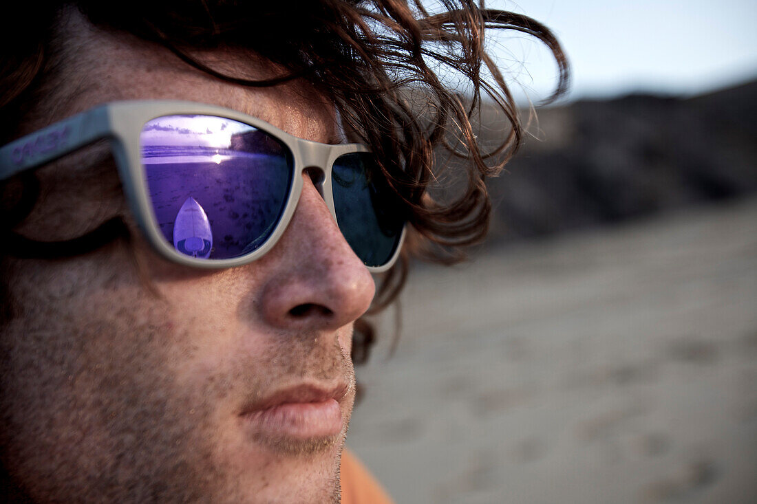 Junger Mann mit Sonnenbrille am Strand, Istmo de la Pared, Fuerteventura, Spanien