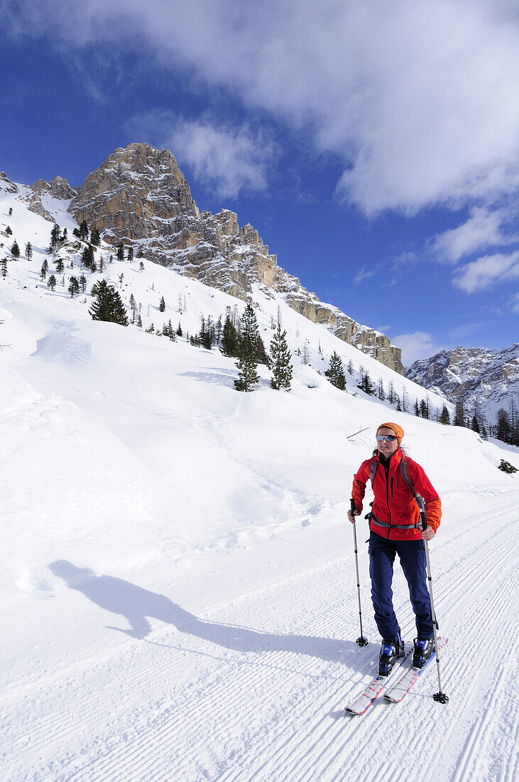 Frau auf Skitour steigt auf präparierter Almstraße auf, Fanes-Sennes-Gruppe im Hintergrund, Naturpark Fanes-Sennes, UNESCO Weltkulturerbe, Dolomiten, Südtirol, Italien