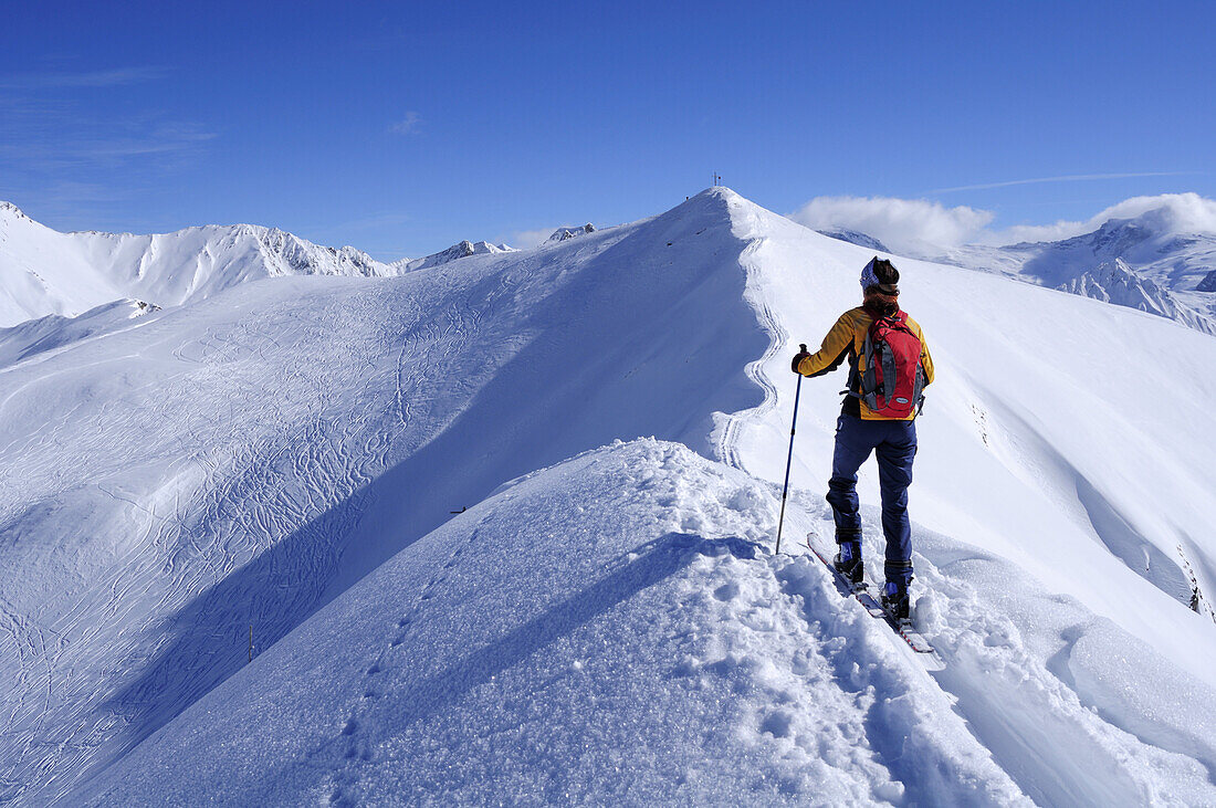 Woman backcountry skiing ascending mountain on snow-covered ridge, Kreuzjoechl, Tuxer Alpen range, Tyrol, Austria