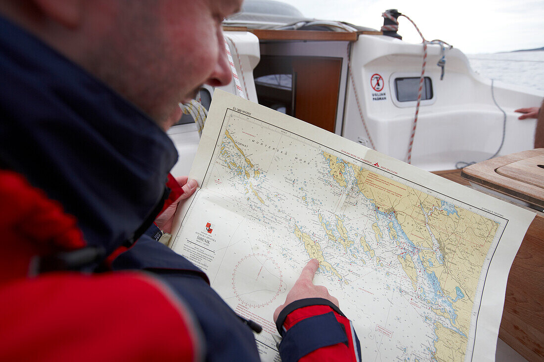 Sailor pointing at a map of Kornati archipelago on a sailing boat, Croatia, Europe