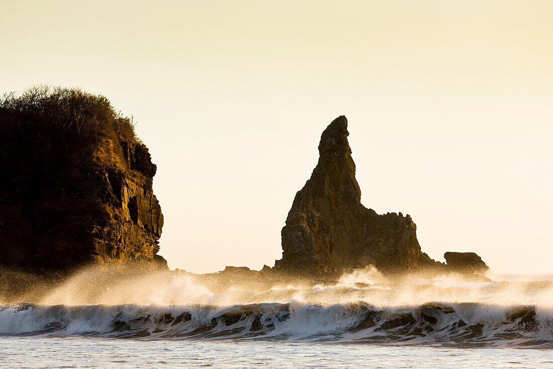 Waves crashing on the shore at sunset by the cliffs of Playa Majagual, Nicaragua