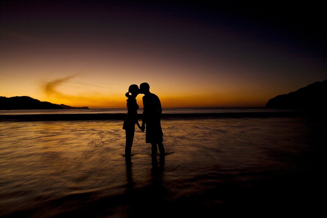 Silhouette of young couple kissing on the beach during sunset at Playas del Coco, Costa Rica