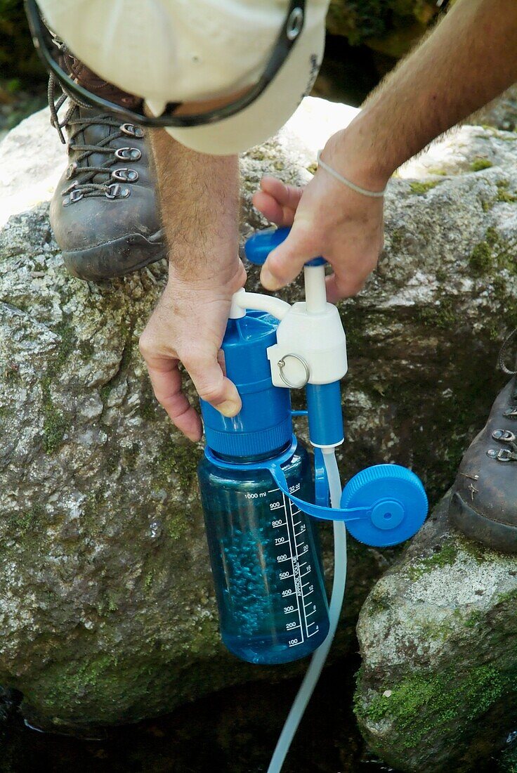 A hiker uses a water filtering system on Meader Ridge Trail during the spring months  Located in the White Mountains, New Hampshire USA  Note: