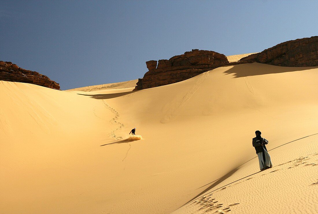 Touareg look at tourist slipping in dune  Oued Tin Tarabine Tassili Ahaggar  Sahara desert  Algeria