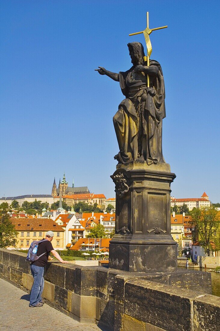 Tourist by statue of John the Baptist on Charles Bridge central Prague Czech Republic EU