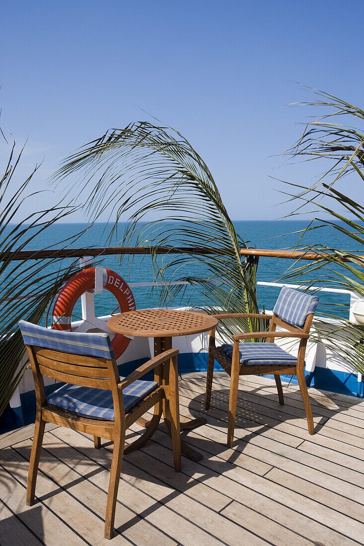 Palmwedel an der Reling und Stühle und Tische an Deck von  Kreuzfahrtschiff MS Delphin (Hansa Kreuzfahrten) in der Karibik