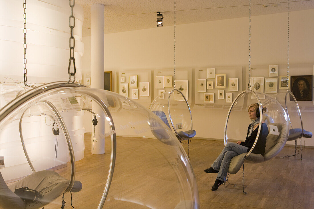 Young woman listens to music in listening pod of Bachhaus Museum, birthplace of Johann Sebastian Bach, Eisenach, Thuringia, Germany, Europe