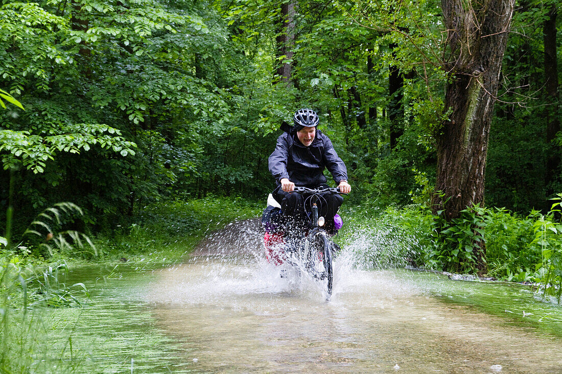 Fahrradfahrer fährt über überschwemmten Isarradweg, Isarauen bei Moosburg, Oberbayern, Deutschland