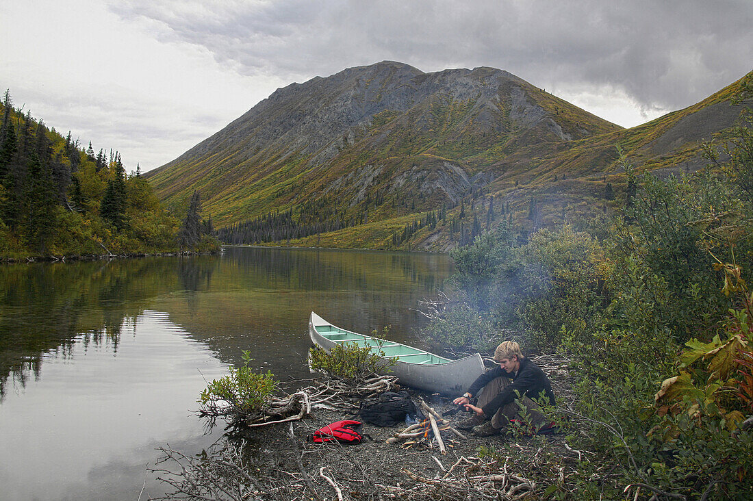 Man sitting at a campfire nwar St. Elias Lake, Kluane National Park and Reserve, Yukon Territory, Canada