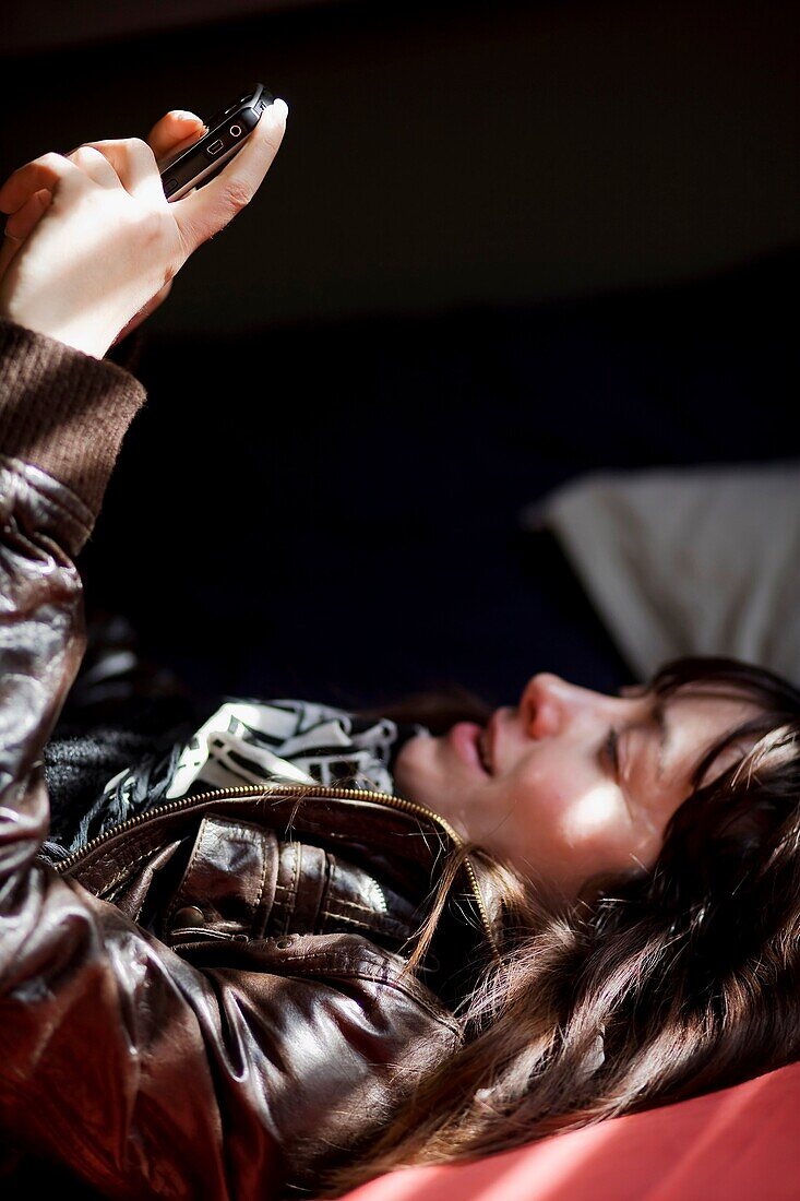 Mujer mirando un telefono móvil en la cama