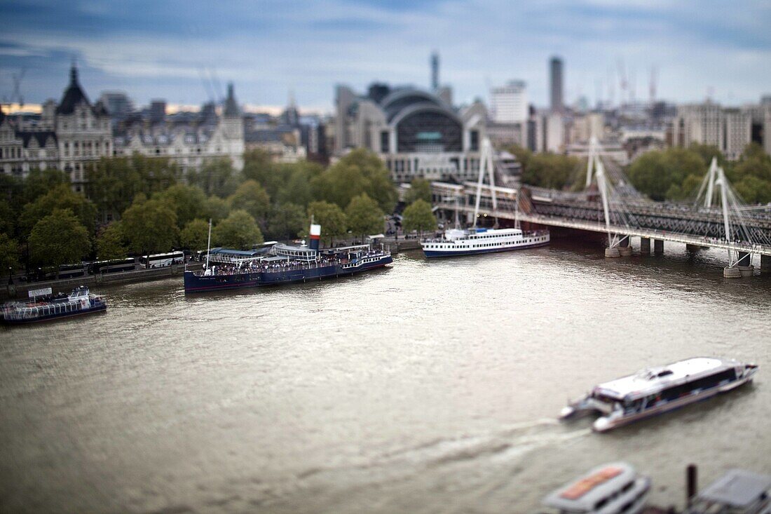 Aerial view of ships and boats on the Thames river with the Hungerford bridge on the background, London, England, United Kingdom Tilted lens used for shallow depth of field