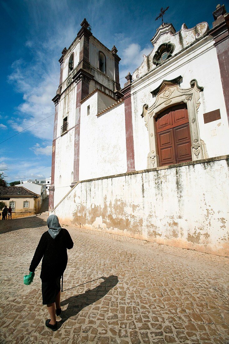 Old woman in front of Misericordia church, town of Silves, district of Faro, region of Algarve, Portugal