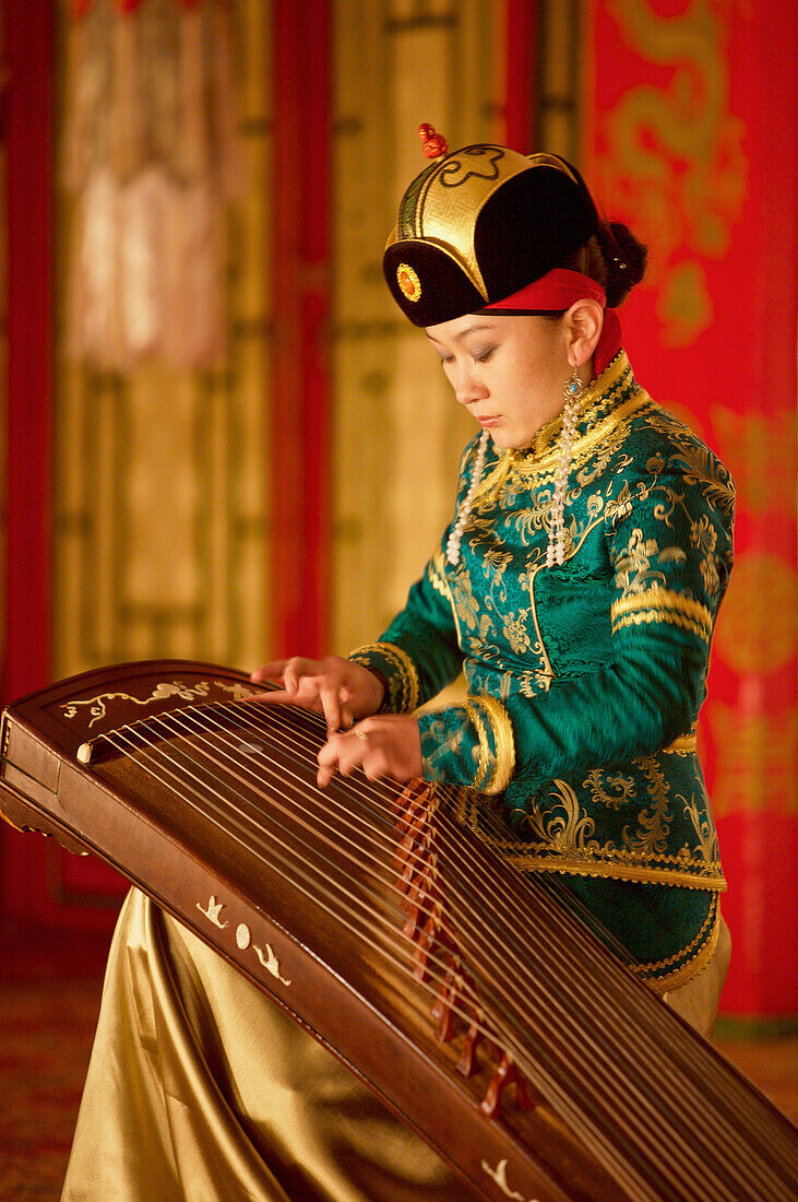 Mongolia, Ulaan Baatar. The Tumen Ekh Folk and Dance Group. Young girl playing antique instrument