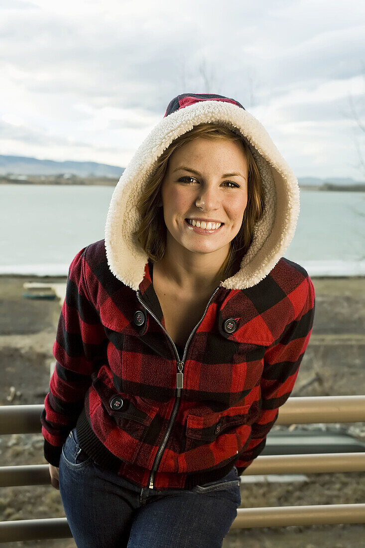 A beautiful young woman standing on a deck in front of a frozen lake in Colorado  USA) smiling