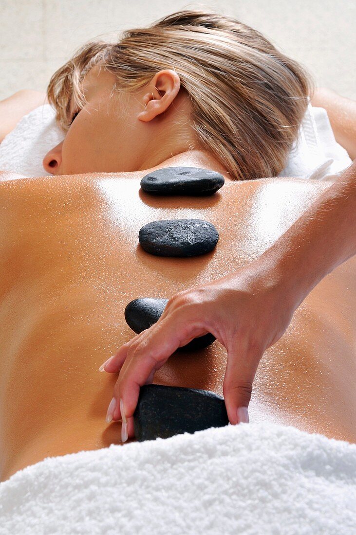 Hand placing hot stone for therapy