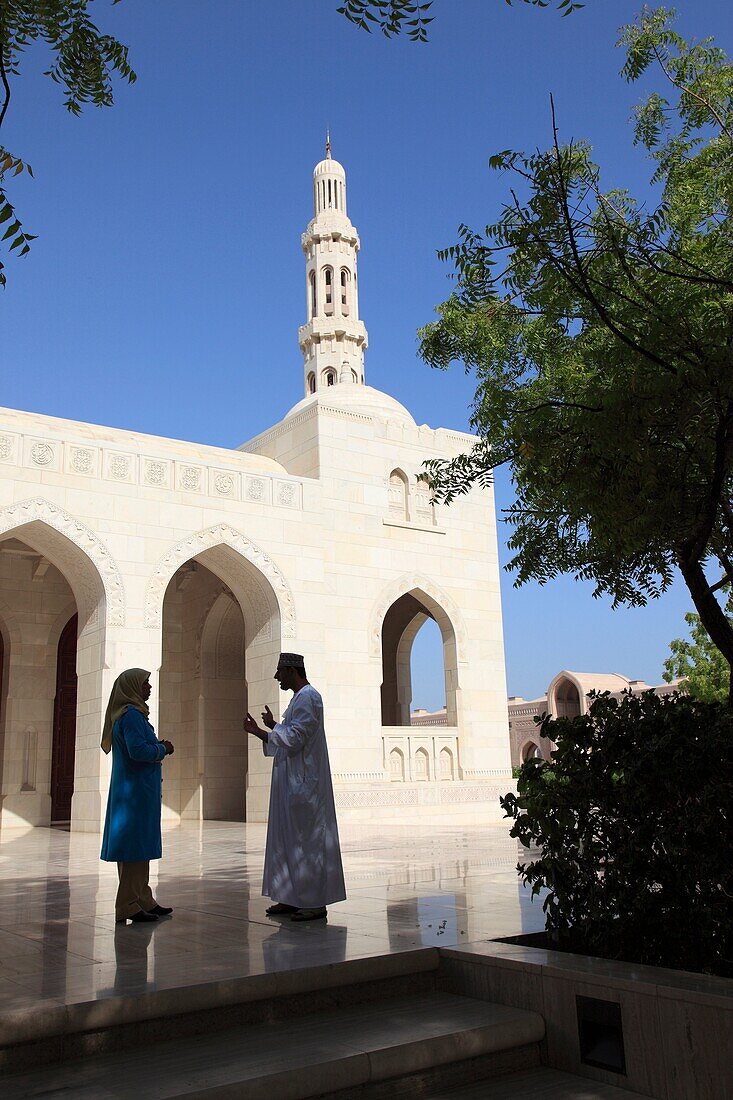Omani man and woman talking outside in front of Grand Mosque Sultan Qaboos, Muscat, Sultanat of Oman, Asia.