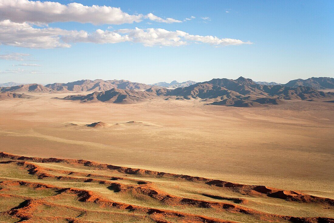 Namibia - Aerial view of sand dunes and isolated mountain ridges at the edge of the Namib Desert In March during the rainy season with a delicate carpet of green desert grass NamibRand Nature Reserve, Namibia