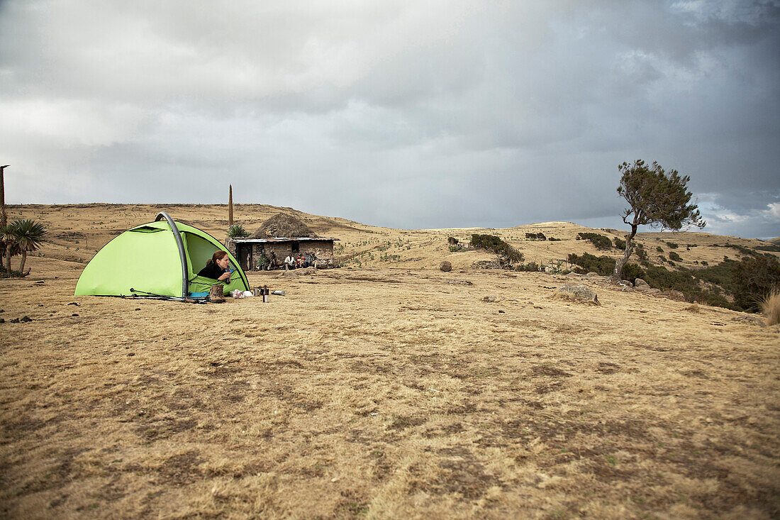 Frau liegt im Zelt unter Wolkenhimmel, Simien Nationalpark, Äthiopien, Afrika