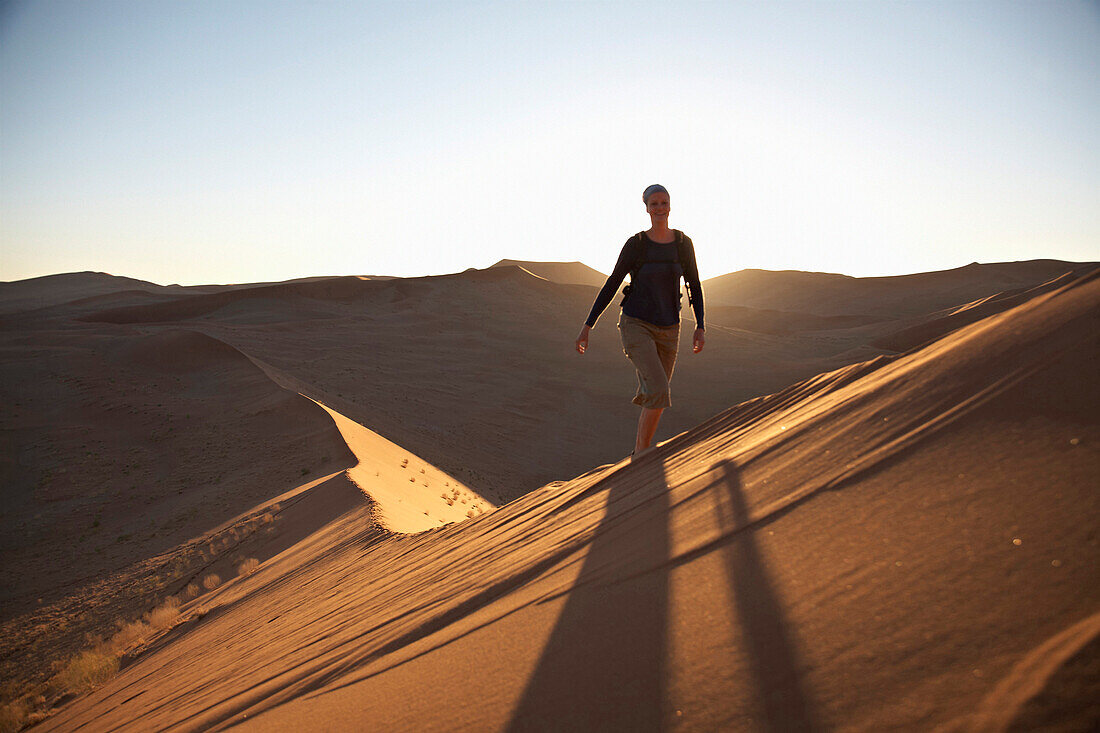 Frau läuft über rote Sanddüne, Namib Naukluft Park, Namibia, Afrika