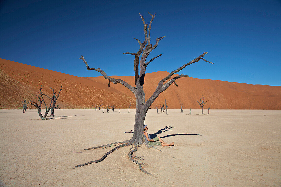 Frau lehnt an Baum, Salzsee mit toten Bäumen, Namib Naukluft Park, Sossusvlei, Namibia, Afrika