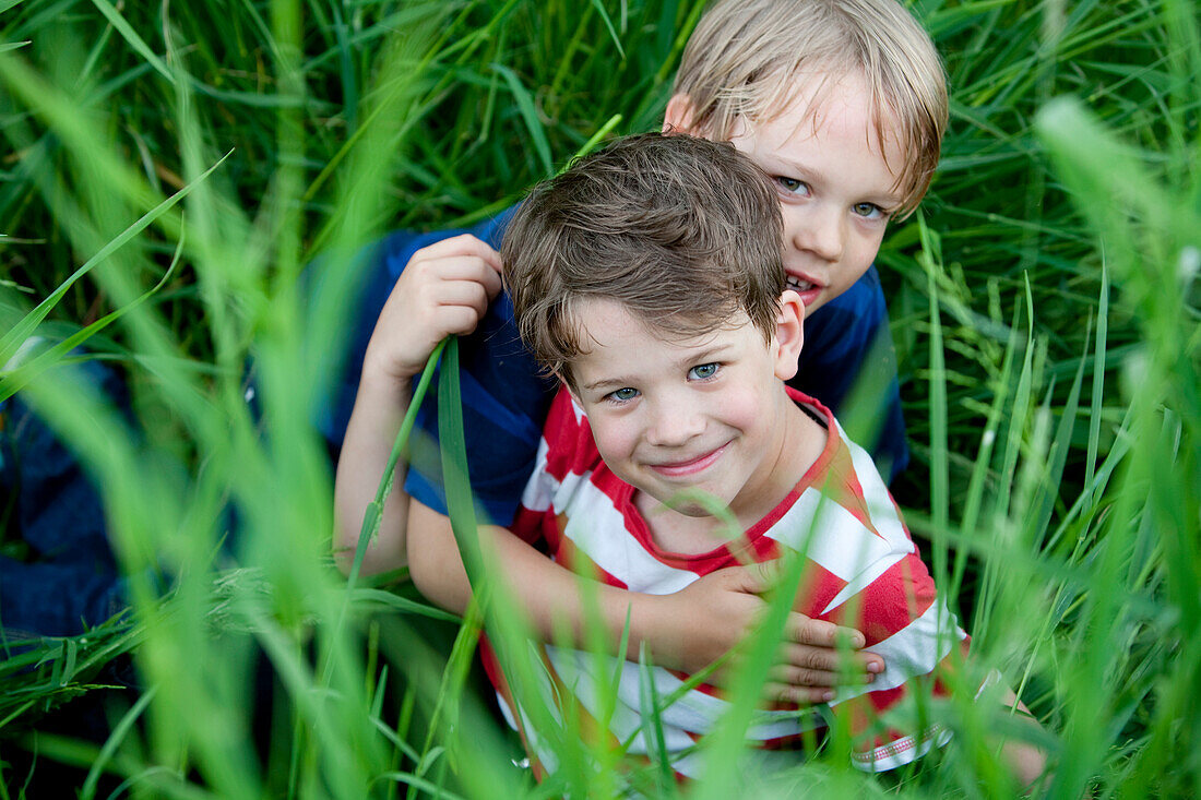 Zwei Jungen (6 - 7 Jahre) sitzen im Gras