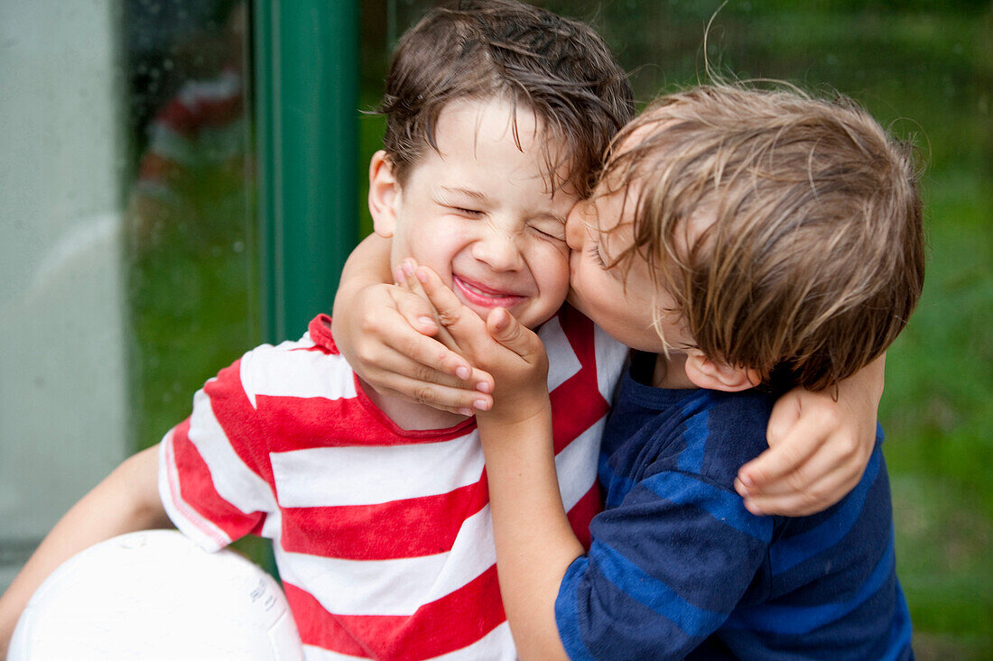 Junge (6 - 7 Jahre) küsst Freund auf die Wange