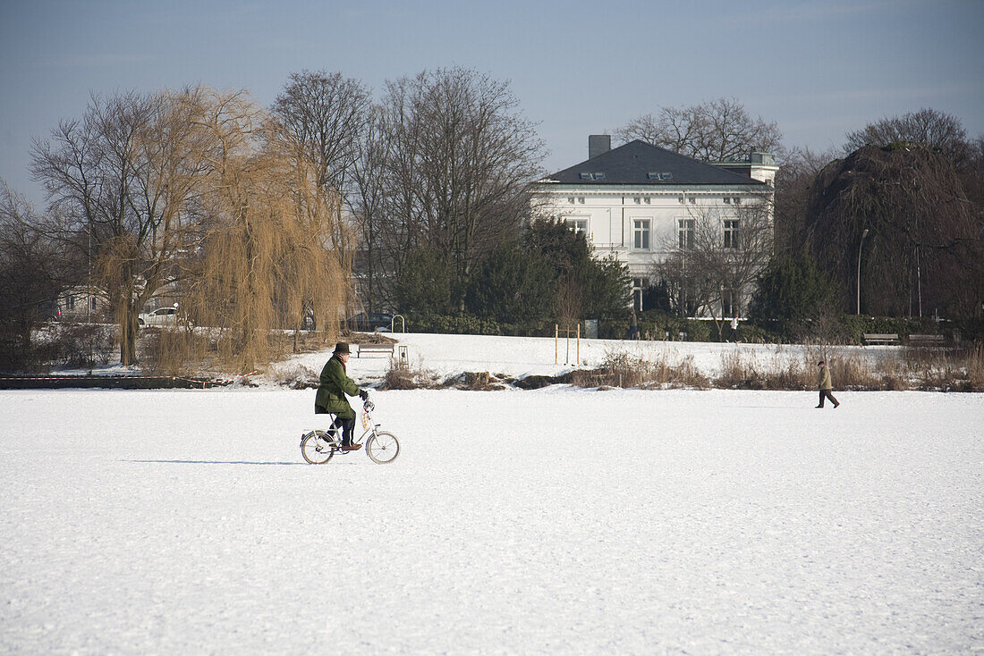 Cyclist on frozen outer Alster in winter, Hamburg, Germany
