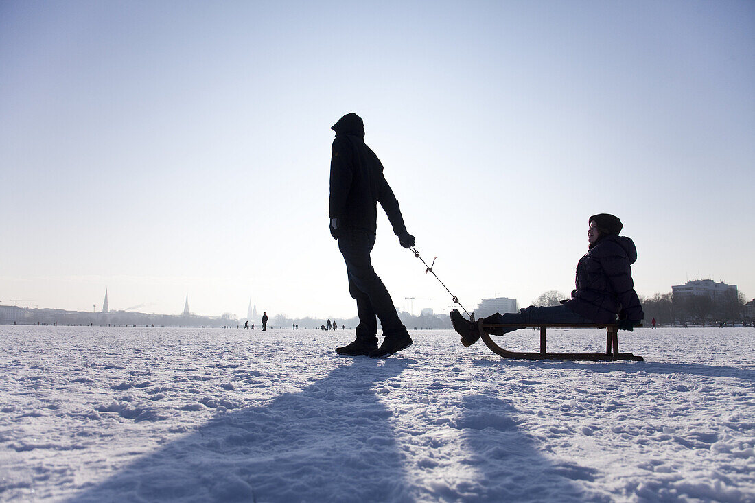 Two persons with sledge on frozen outer Alster in winter, Hamburg, Germany