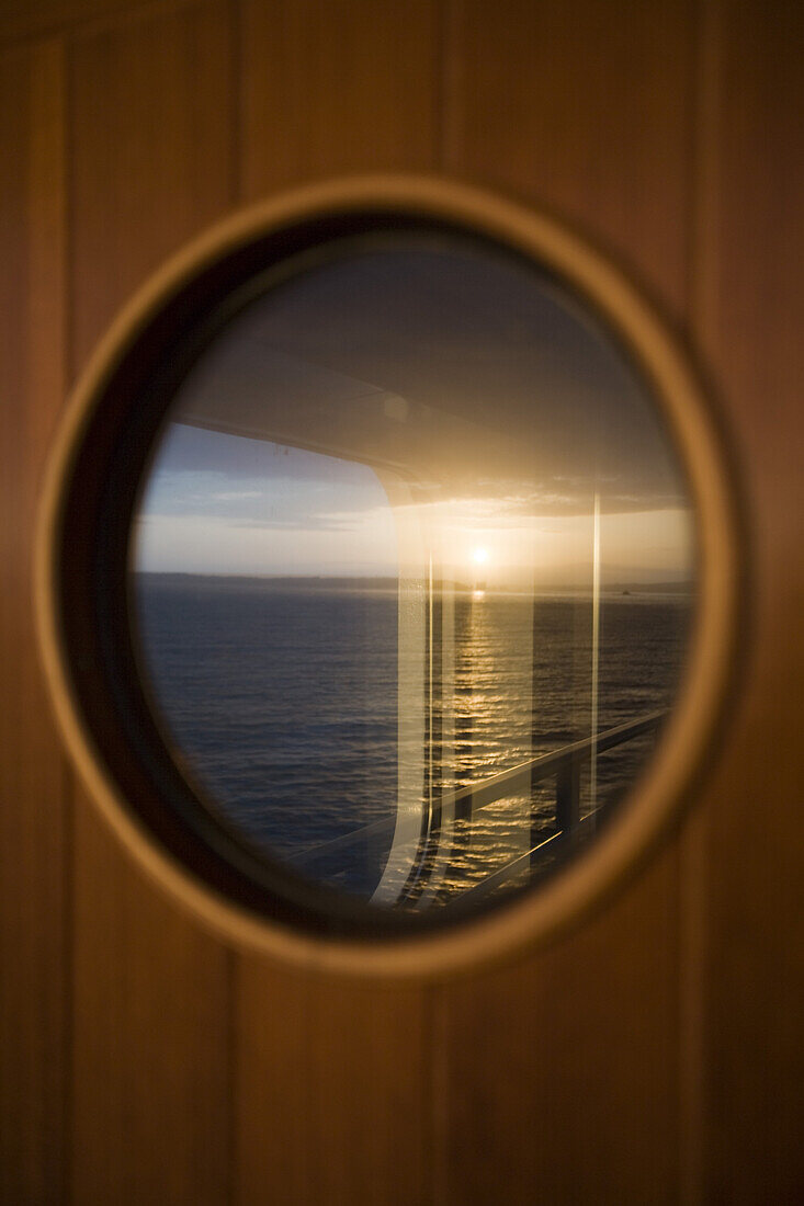 Spiegelung des Sonnenaufgangs in einem Fenster auf Kreuzfahrtschiff Silver Spirit, Atlantik, Europa