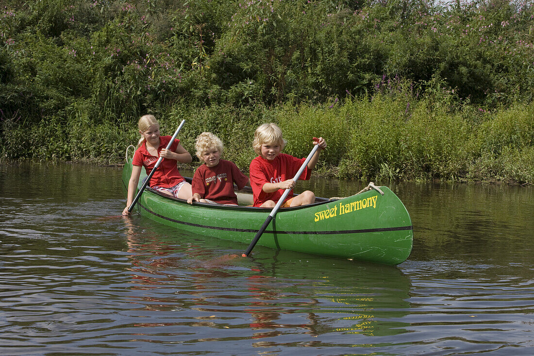 Three children paddling a canoe on the river Fulda, Niederaula, Hesse, Germany, Europe