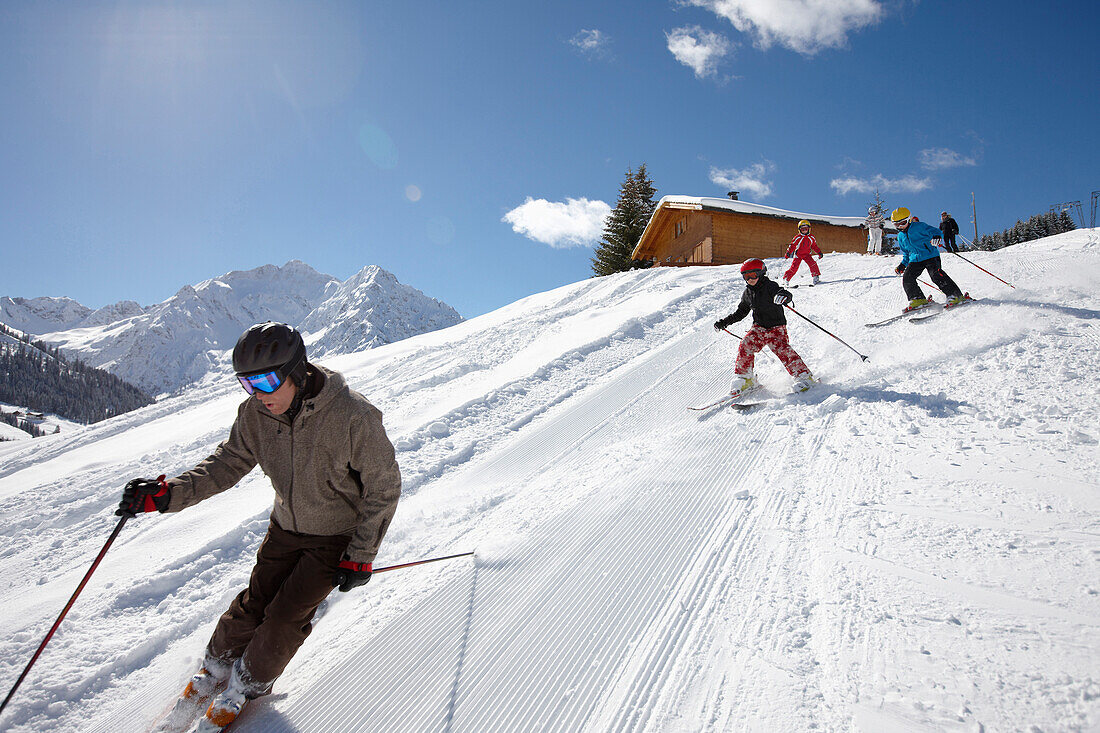 Familie fährt Ski auf frisch präparierte Piste, Schlößlelift, Hirschegg, Kleinwalsertal, Vorarlberg, Österreich