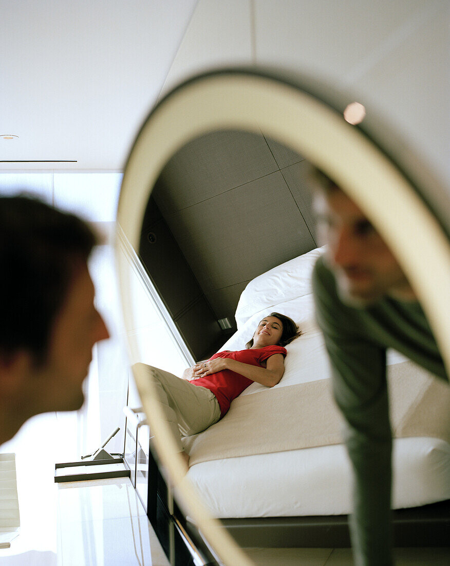 Man looking into the mirror, Woman lying on the bed watching, Hotel room on the 2nd Floor, Designed by Norman Foster, Hotel Silken Puerta America, Madrid, Spain