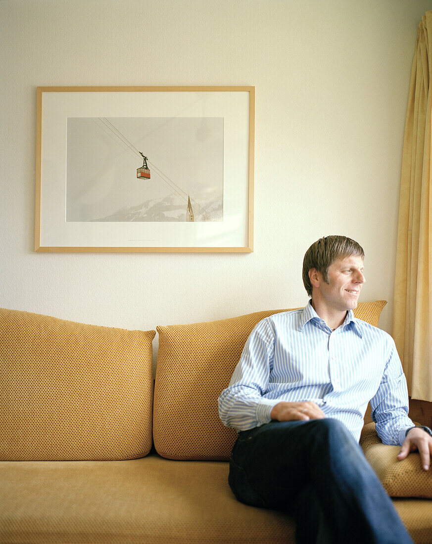 Man relaxing on the sofa, Room in the organic Naturhotel Chesa Valisa, Hirschegg, Kleinwalsertal, Austria