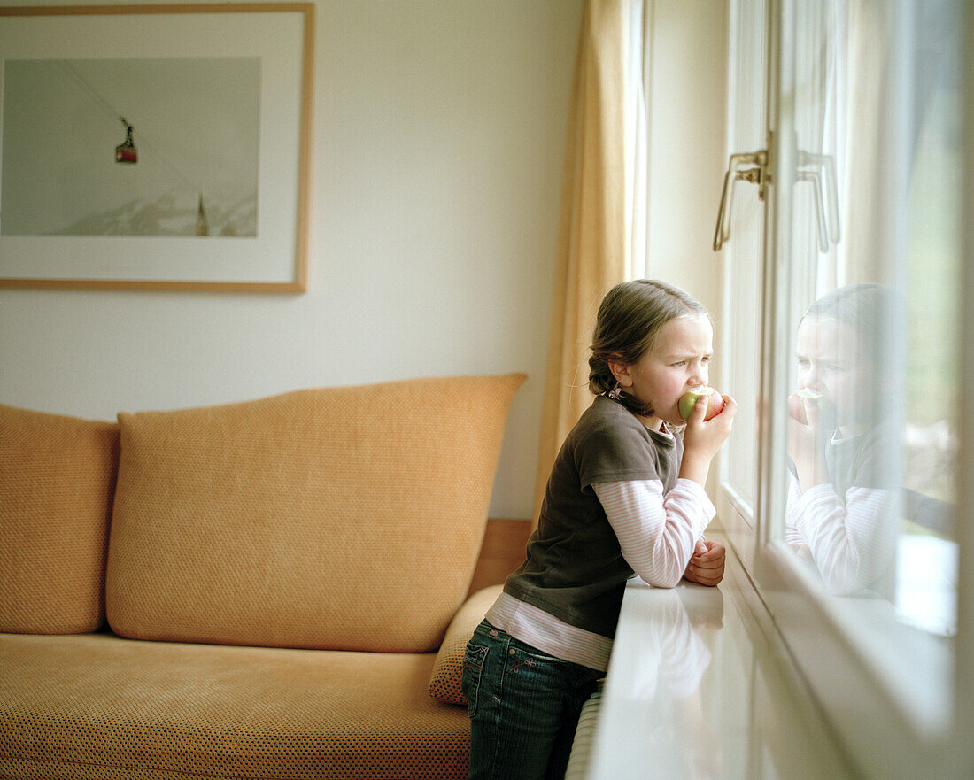 Girl looking out of the window, eating an apple, Hotel room, organic Hotel Chesa Valisa, Hirschegg, Kleinwalsertal, Austria