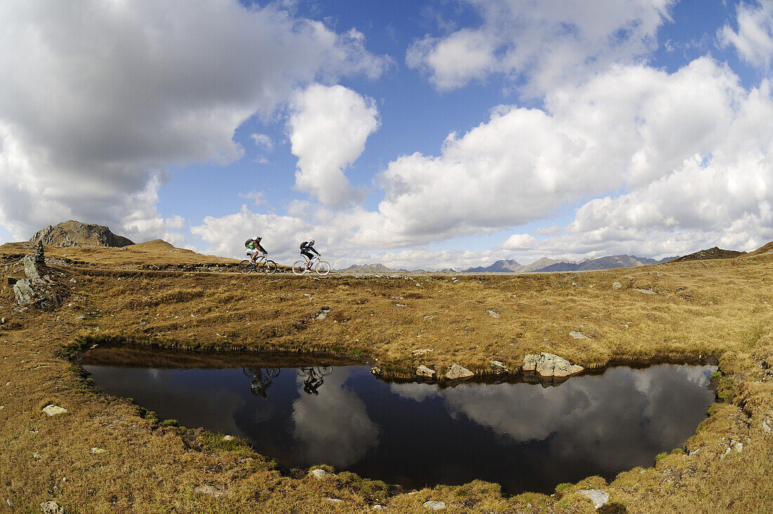 Mountainbiker vor Bergsee unter Wolkenhimmel, Markinkele, Innichen, Hochpustertal, Südtirol, Dolomiten, Italien, Europa