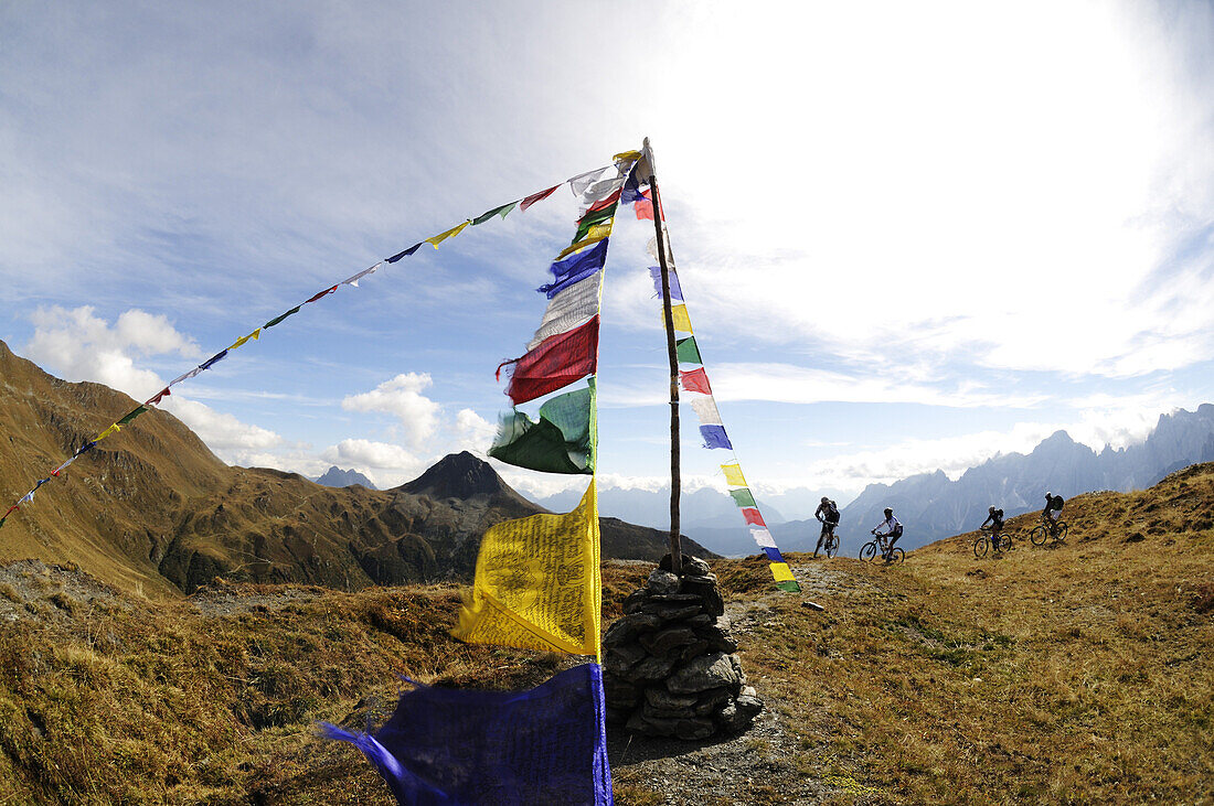 People on mountain bikes at Karnischer Höhenweg next to prayer flags, Dolomites, South Tyrol, Italy, Europe