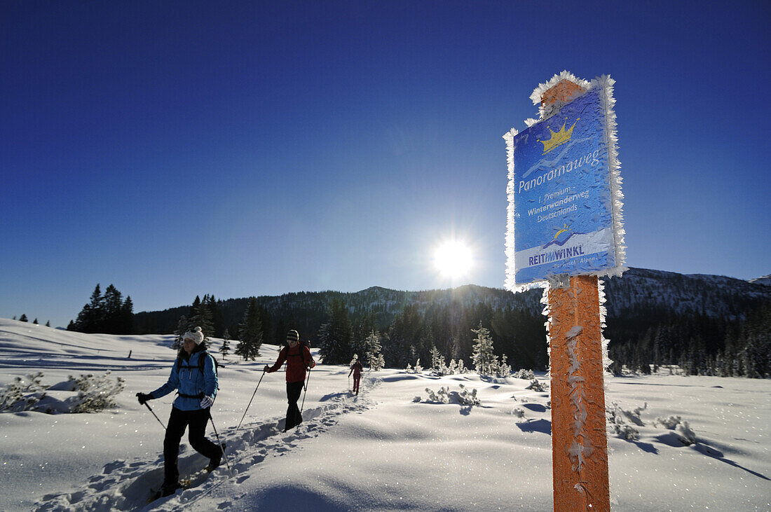 Snowshoeing people and frosted sign in winter landscape, Hemmersuppenalm, Reit im Winkl, Chiemgau, Upper Bavaria, Bavaria, Germany, Europe