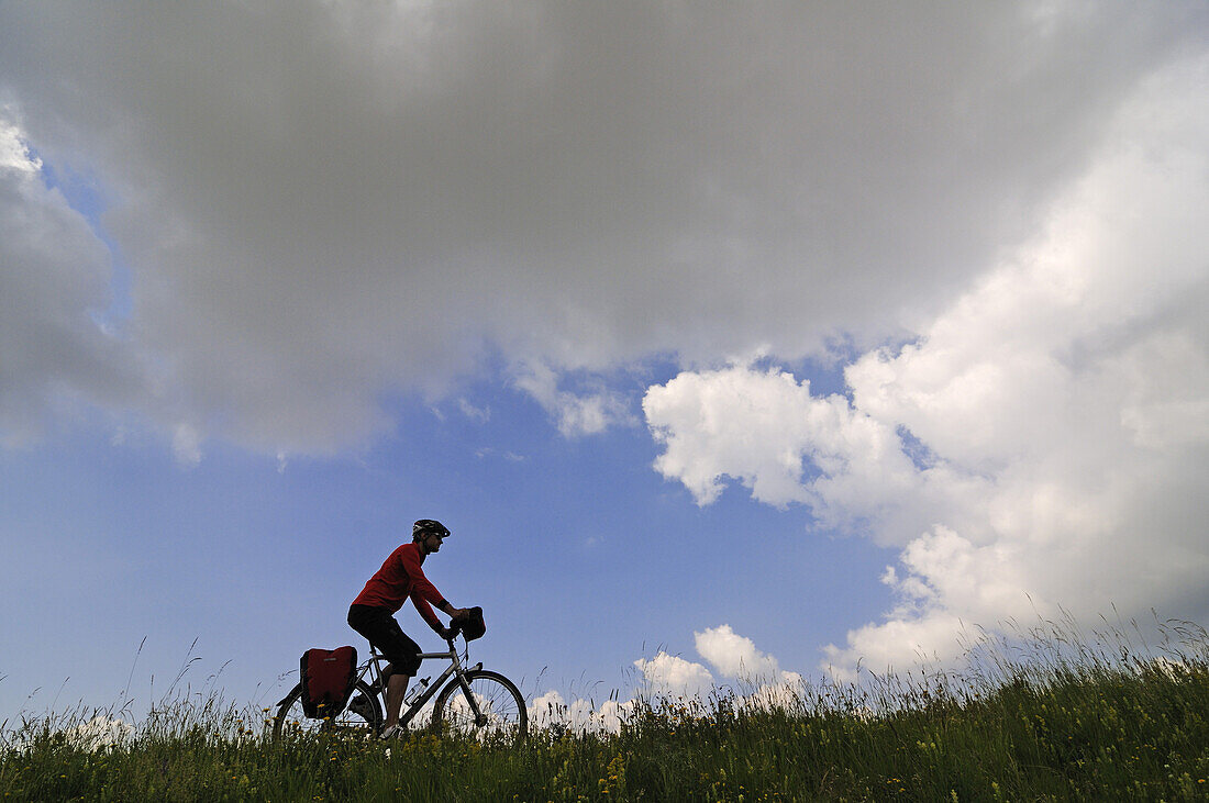Cyclist beneath clouds at Campo Imperatore, Gran Sasso National Park, Abruzzi, Italy, Europe