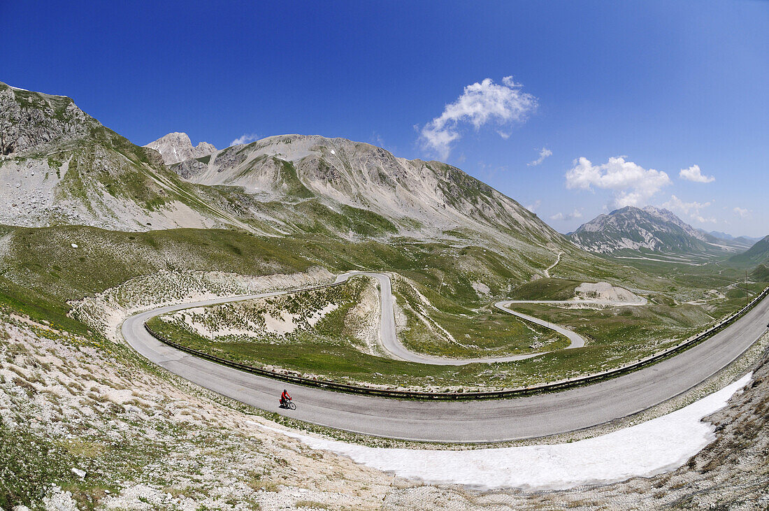 Cyclist on country road at Campo Imperatore, Gran Sasso National Park, Abruzzi, Italy, Europe