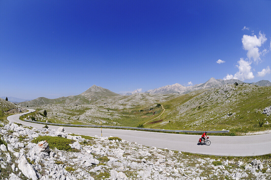 Radfahrer auf einsamer Landstrasse, Castel del Monte, Campo Imperatore, Abruzzen, Italien, Europa