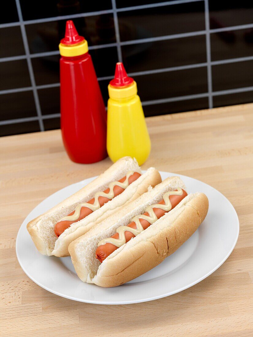 A hotdog with mustard sauce on a kitchen bench